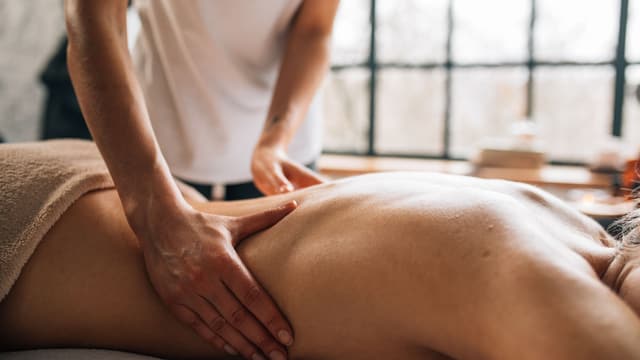 A massage therapist working along a client's back with long, flowing strokes.