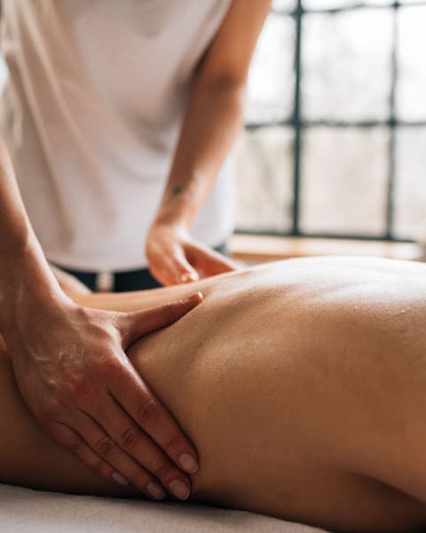 A massage therapist working along a client's back with long, flowing strokes.
