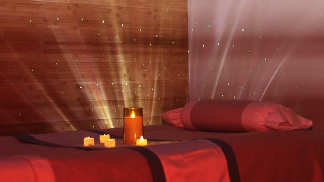 A candle and tealights on a massage table at Wonder Spa, with soft light rays and green star points across the cedar wall.