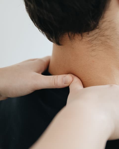 Hands applying focused pressure to the neck and upper shoulder.